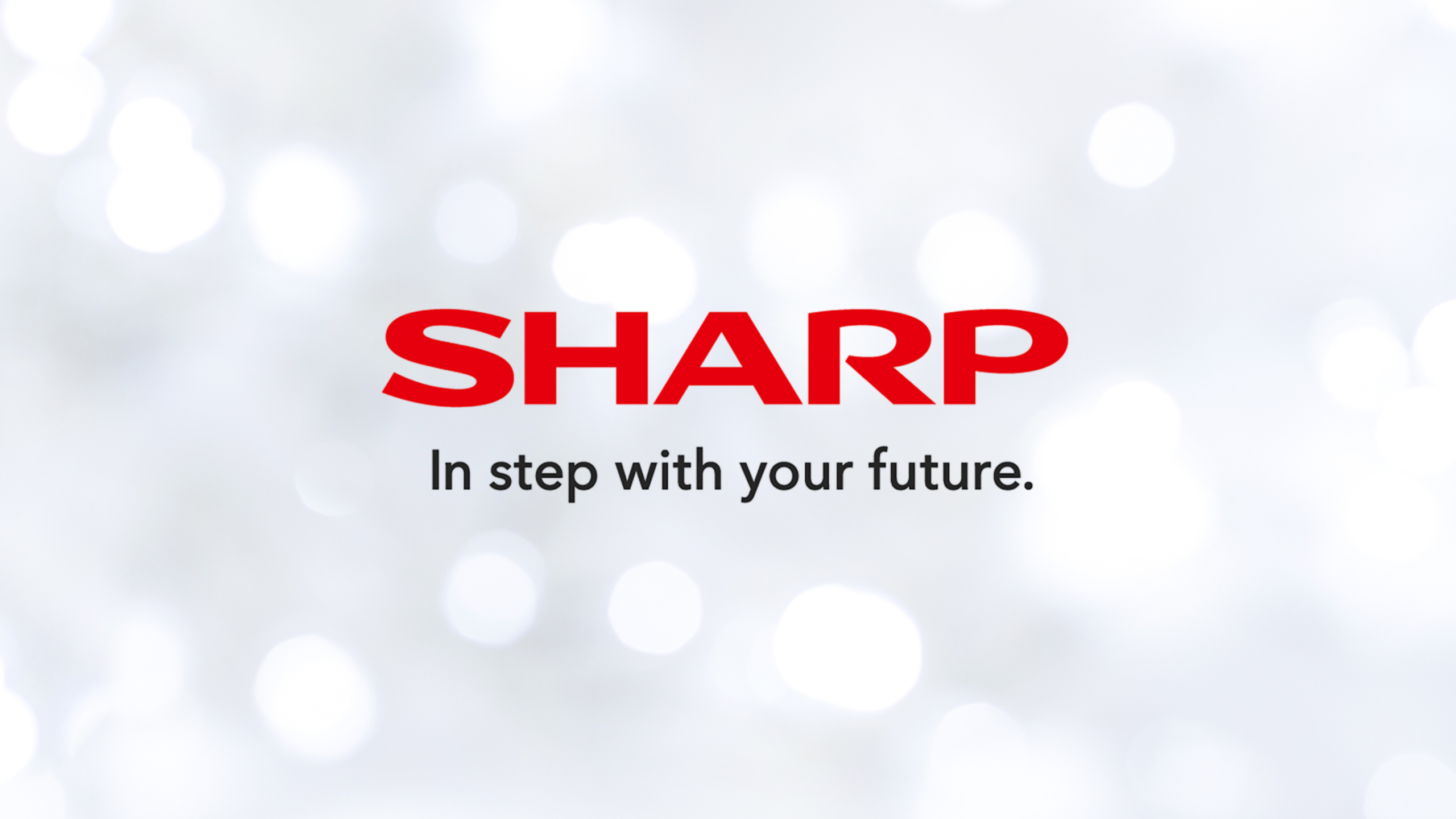 The image shows the sharp logo in bold red letters above the slogan in step with your future On a blurred light background with white bokeh effects