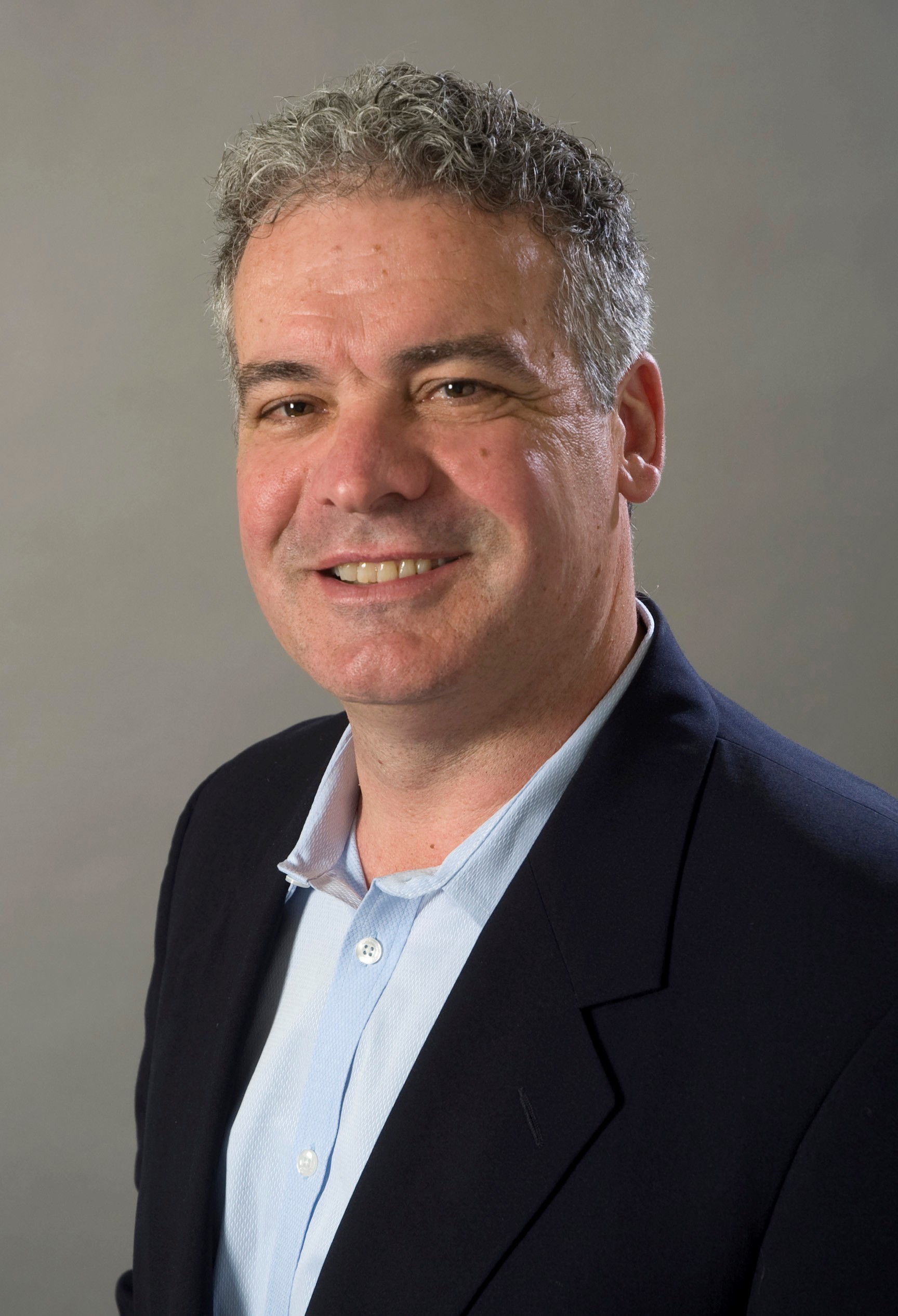 Robert bob madonna of savant a man with short curly gray hair is smiling at the camera He is wearing a dark blazer over a light blue collared shirt against a plain neutral background