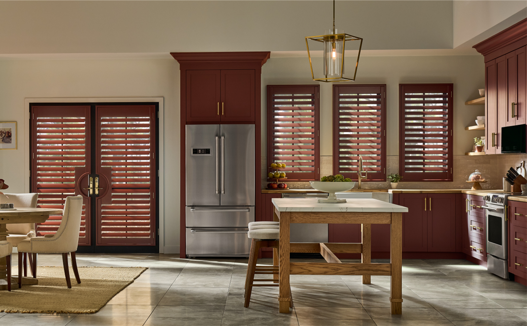 Modern kitchen with maroon cabinets wooden shutters stainless steel fridge and a wood island with white countertop A gold pendant light shines as natural light enters through large windows featuring smarter window design for spring 2026 Modern kitchen with maroon cabinets wooden shutters stainless steel fridge and a wood island with white countertop A gold pendant light shines as natural light enters through large windows featuring smarter window design for spring 2026 Graber introduces a smarter softer approach to window coverings and design for spring 2026