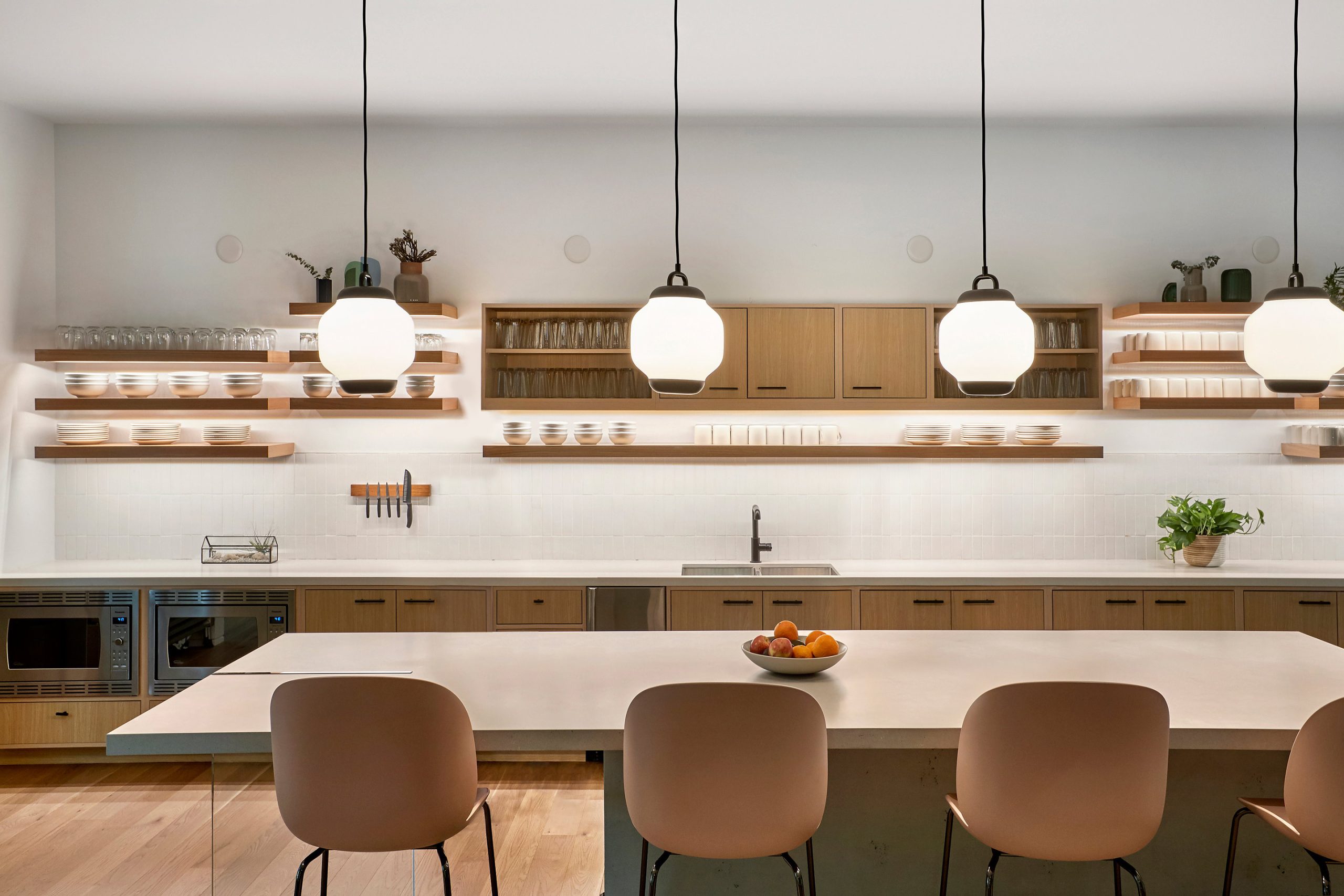 Modern kitchen with light wood cabinets open shelves displaying dishes a white countertop island with four light pink chairs pendant lights above and lit luxury integrated technologies seamlessly enhancing the space Modern kitchen with light wood cabinets open shelves displaying dishes a white countertop island with four light pink chairs pendant lights above and lit luxury integrated technologies seamlessly enhancing the space Luxury integrated technologies its lit
