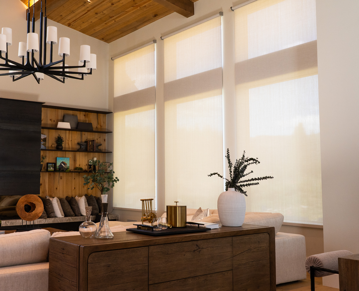 Modern living room with tall windows covered by light shades a wood ceiling beige sofas a wooden coffee table with decor and wall shelves holding plants and ornaments Modern living room with tall windows covered by light shades a wood ceiling beige sofas a wooden coffee table with decor and wall shelves holding plants and ornaments Cedia expo 2026 product showcase